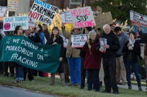 Group of people marching against fracking. Signs read Help Up stop Fracking, We demand a moratorium on fracking, Water for farming NOT fracking, and Save Tourism Stop Fracking.