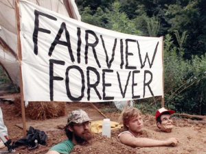 3 People buried in the ground with just their heads and arms above ground. A banner behind them reads Fairview Forever