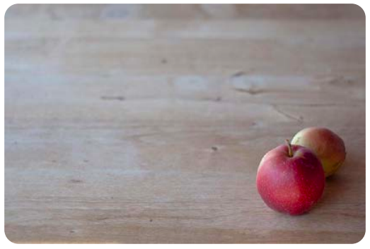 red apples are clustered in one corner of a wooden table