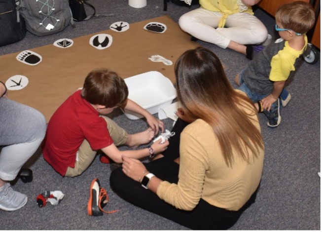 A child engaging in a footprint activity with the help of an aide.